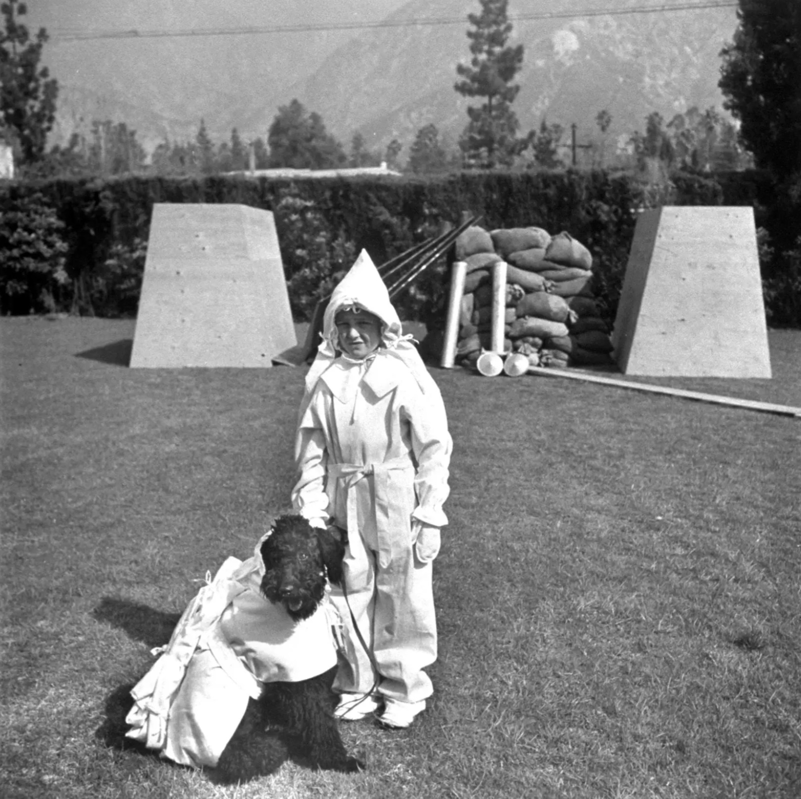 A boy and his dog model the latest fashions in atomic protection in front of their bomb shelter 